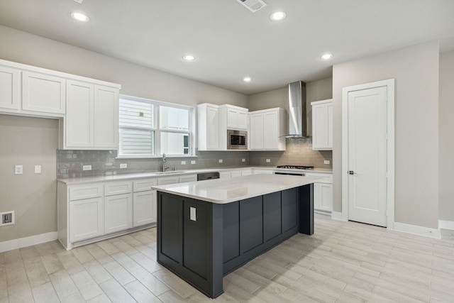 kitchen with white cabinetry, a kitchen island, stainless steel microwave, and wall chimney exhaust hood