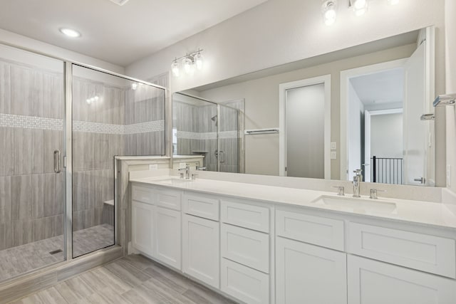 bathroom featuring a shower with door and vanity