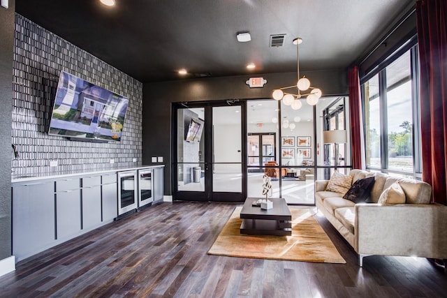 living room with dark wood-style flooring, an inviting chandelier, an accent wall, baseboards, and visible vents