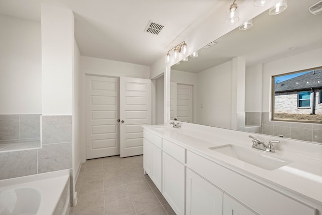 bathroom with a relaxing tiled tub, tile patterned floors, and vanity