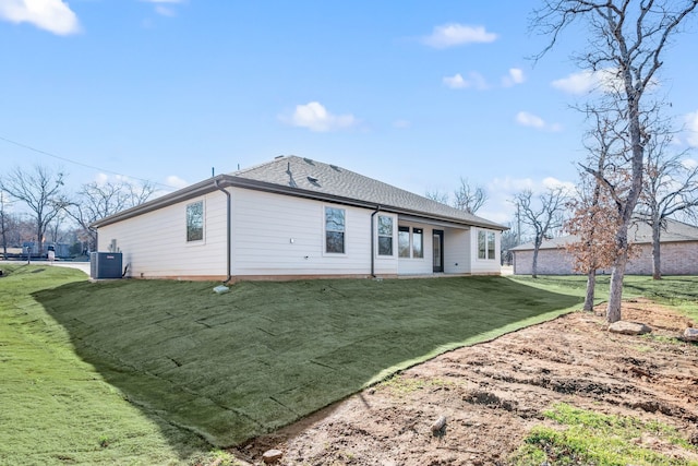 back of property with central AC unit and a yard