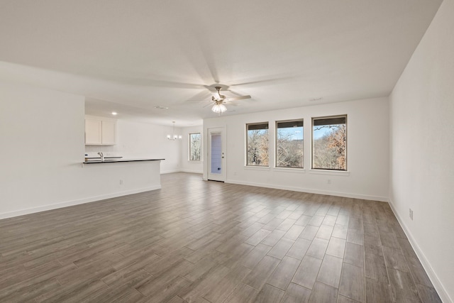 unfurnished living room with sink, dark hardwood / wood-style floors, and ceiling fan with notable chandelier