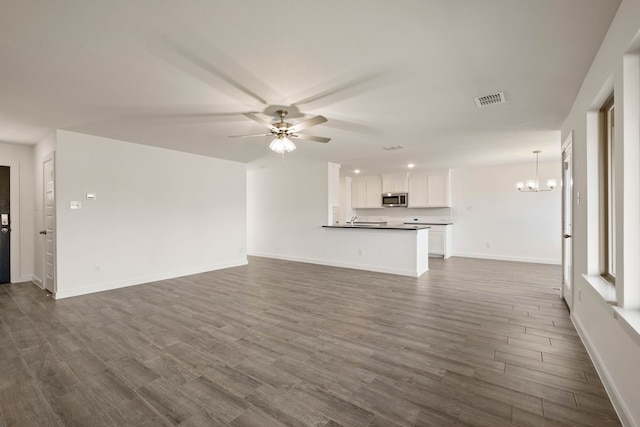 unfurnished living room featuring sink, ceiling fan with notable chandelier, and dark wood-type flooring