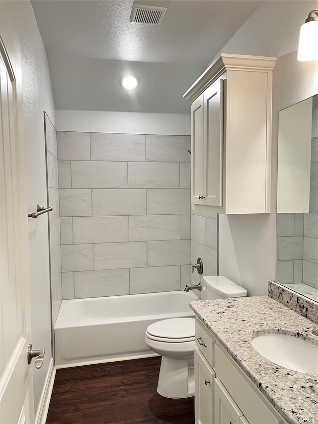 full bathroom with vanity, a textured ceiling, hardwood / wood-style floors, toilet, and tiled shower / bath