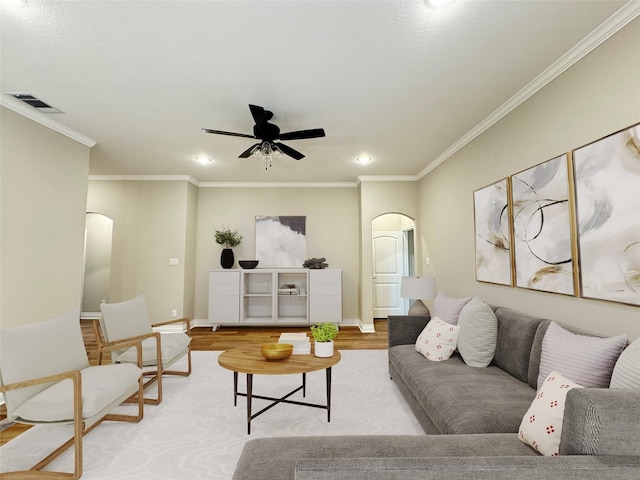 living room featuring crown molding, ceiling fan, and light wood-type flooring