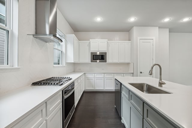 kitchen with dark wood-type flooring, sink, wall chimney range hood, stainless steel appliances, and white cabinets