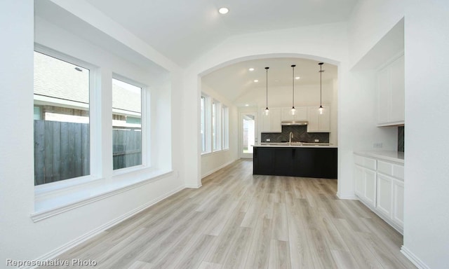 kitchen featuring white cabinetry, sink, decorative backsplash, hanging light fixtures, and light hardwood / wood-style floors