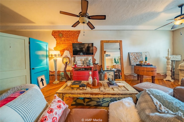 living room with ceiling fan, wood-type flooring, and a textured ceiling