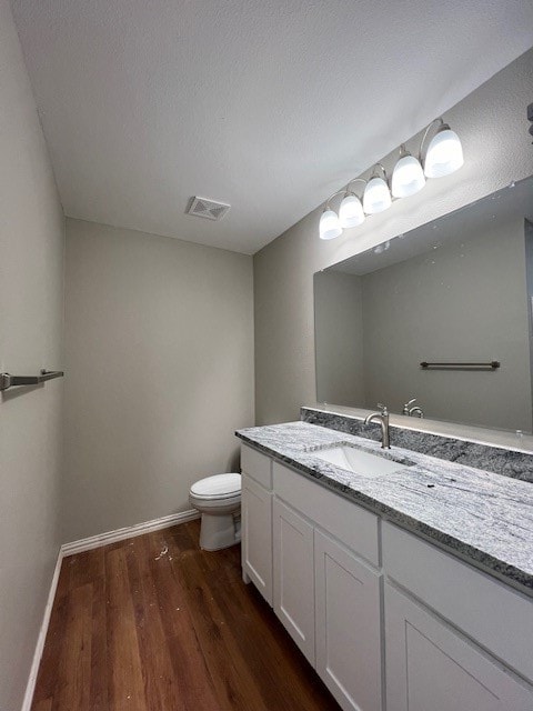 bathroom with a textured ceiling, vanity, hardwood / wood-style flooring, and toilet