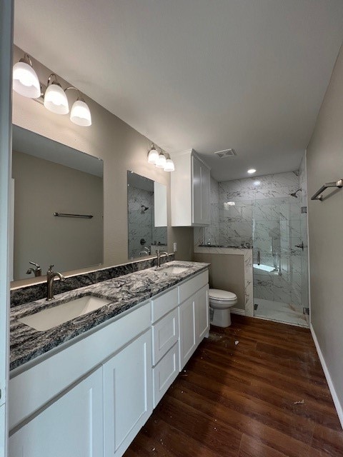 bathroom with a tile shower, toilet, vanity, and hardwood / wood-style flooring