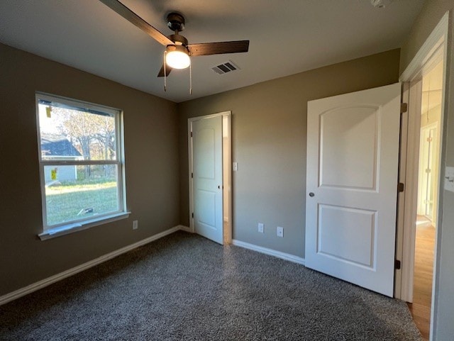 unfurnished bedroom with dark colored carpet and ceiling fan