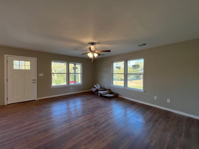 unfurnished living room with dark hardwood / wood-style flooring and ceiling fan