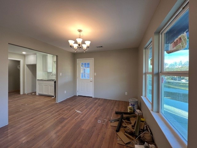 interior space with an inviting chandelier, a healthy amount of sunlight, and hardwood / wood-style flooring