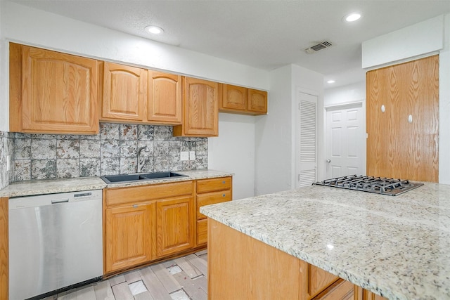 kitchen featuring sink, light stone counters, light hardwood / wood-style flooring, decorative backsplash, and appliances with stainless steel finishes