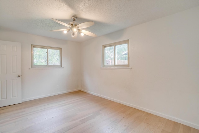 spare room with ceiling fan, light wood-type flooring, a textured ceiling, and a wealth of natural light