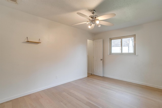 empty room featuring ceiling fan, light wood-type flooring, and a textured ceiling