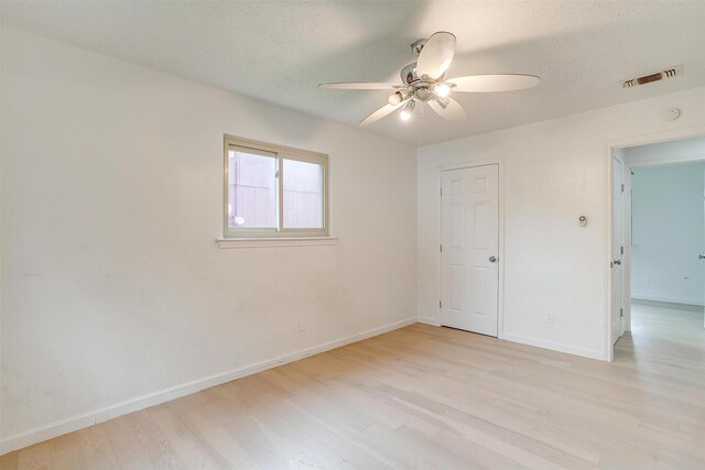 unfurnished room featuring ceiling fan, light hardwood / wood-style floors, and a textured ceiling