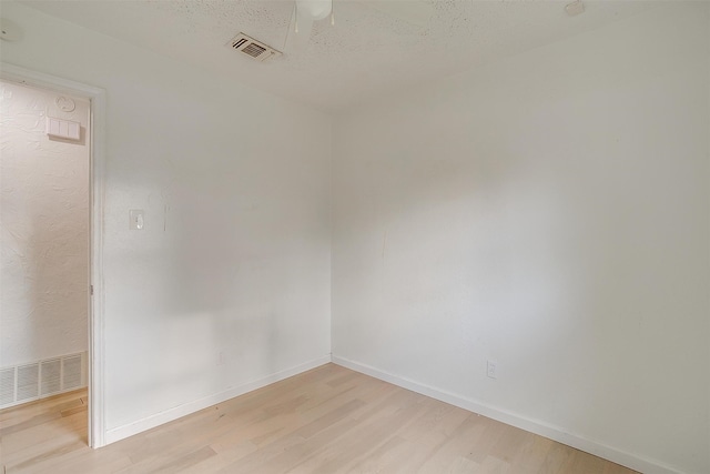 spare room with a textured ceiling and light hardwood / wood-style flooring