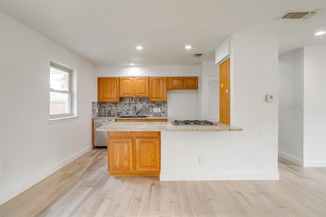 kitchen featuring backsplash, kitchen peninsula, light hardwood / wood-style floors, and appliances with stainless steel finishes