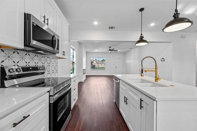 kitchen with pendant lighting, sink, a kitchen island with sink, stainless steel appliances, and white cabinets