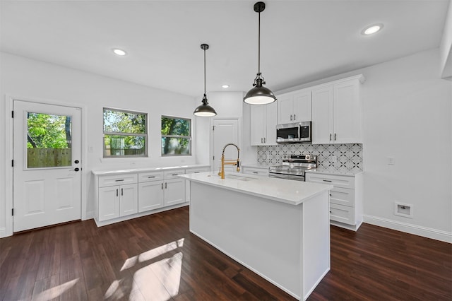 kitchen with sink, white cabinetry, appliances with stainless steel finishes, an island with sink, and pendant lighting