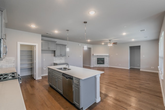 kitchen with gray cabinets, ceiling fan, an island with sink, and stainless steel appliances