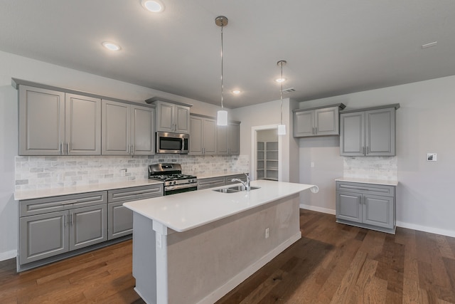 kitchen featuring a kitchen island with sink, sink, dark wood-type flooring, and appliances with stainless steel finishes