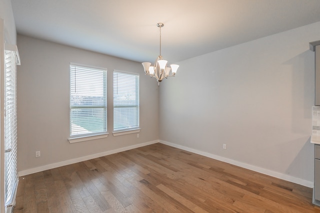 unfurnished room featuring wood-type flooring and a notable chandelier