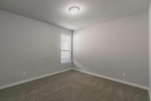 unfurnished room featuring dark carpet