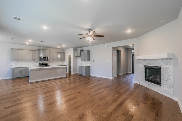 unfurnished living room featuring ceiling fan, dark hardwood / wood-style flooring, and a brick fireplace