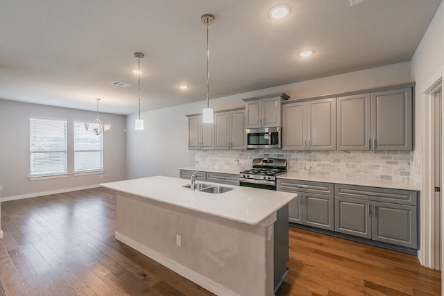 kitchen with dark hardwood / wood-style flooring, sink, a center island with sink, and appliances with stainless steel finishes