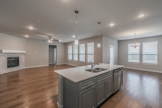 kitchen with stainless steel dishwasher, gray cabinetry, a healthy amount of sunlight, sink, and a center island with sink