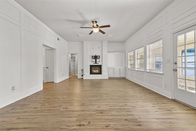 unfurnished living room featuring ceiling fan, light hardwood / wood-style floors, and a brick fireplace