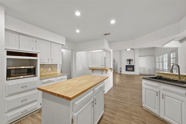 kitchen featuring butcher block countertops, a center island, white cabinetry, and light hardwood / wood-style floors