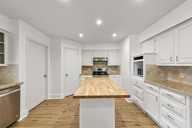 kitchen featuring decorative backsplash, appliances with stainless steel finishes, a kitchen island, light hardwood / wood-style flooring, and white cabinetry