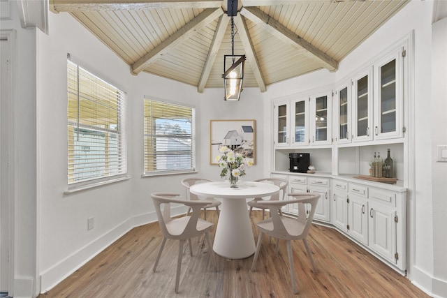 dining room featuring wood ceiling, bar area, lofted ceiling with beams, and light hardwood / wood-style floors