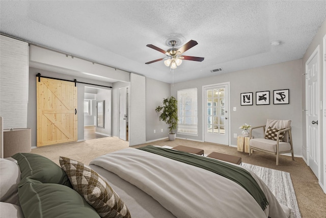 bedroom with access to exterior, ceiling fan, a barn door, a textured ceiling, and light carpet