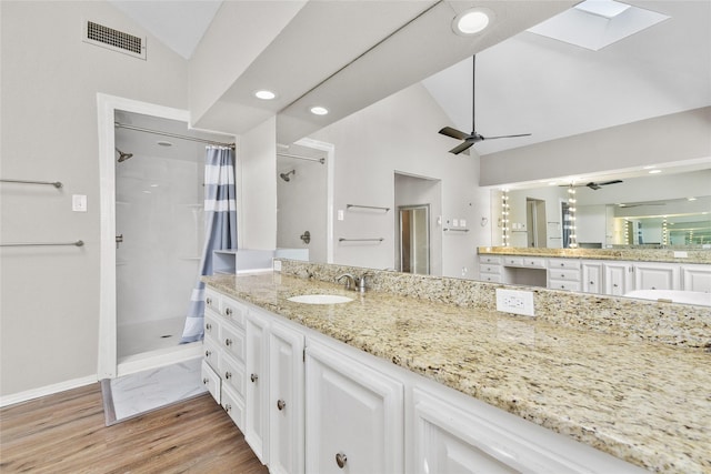 bathroom with hardwood / wood-style flooring, ceiling fan, lofted ceiling with skylight, and a shower with shower curtain