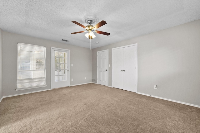 unfurnished bedroom with carpet, a textured ceiling, and ceiling fan