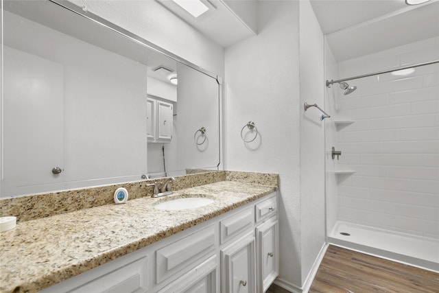 bathroom featuring hardwood / wood-style floors, vanity, and tiled shower