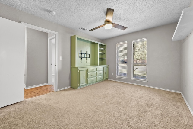 carpeted empty room with ceiling fan and a textured ceiling