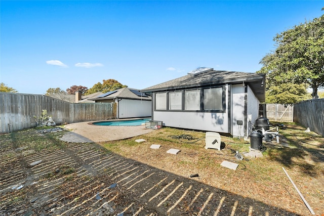 rear view of property featuring a fenced in pool