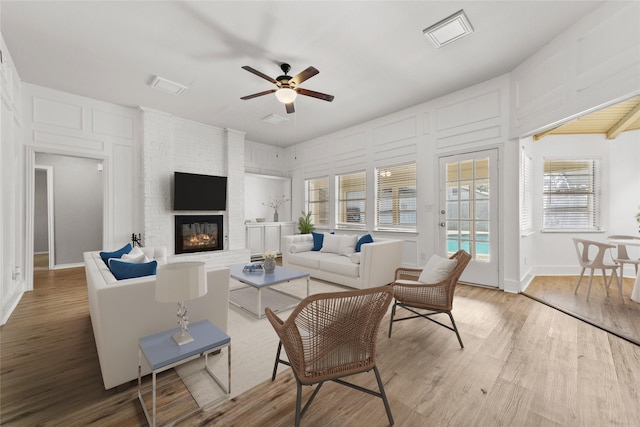 living room with a fireplace, hardwood / wood-style floors, ceiling fan, and a healthy amount of sunlight