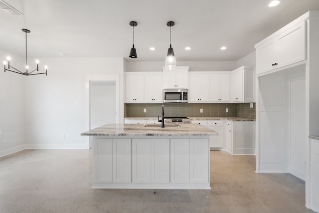 kitchen with tasteful backsplash, white cabinetry, a center island with sink, and sink