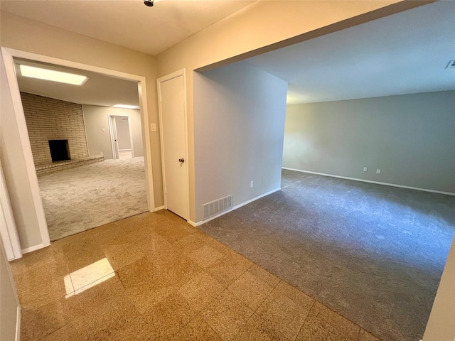 spare room featuring carpet flooring and a fireplace