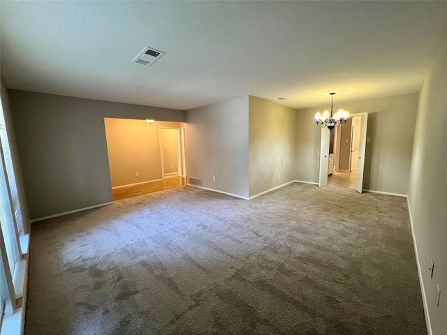 carpeted spare room featuring a notable chandelier