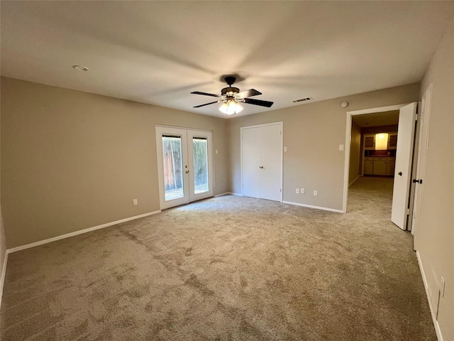 carpeted spare room featuring french doors and ceiling fan