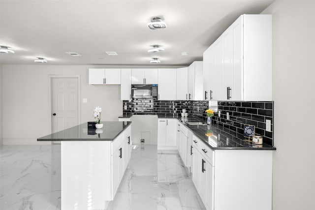 kitchen with tasteful backsplash, white cabinetry, and a kitchen island