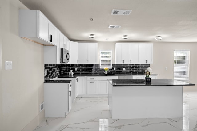 kitchen featuring white cabinets, decorative backsplash, a kitchen island, and a textured ceiling