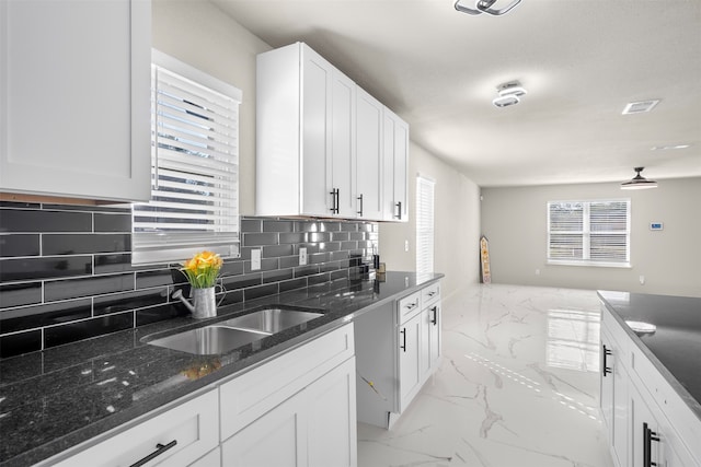 kitchen with decorative backsplash, white cabinetry, a healthy amount of sunlight, and sink